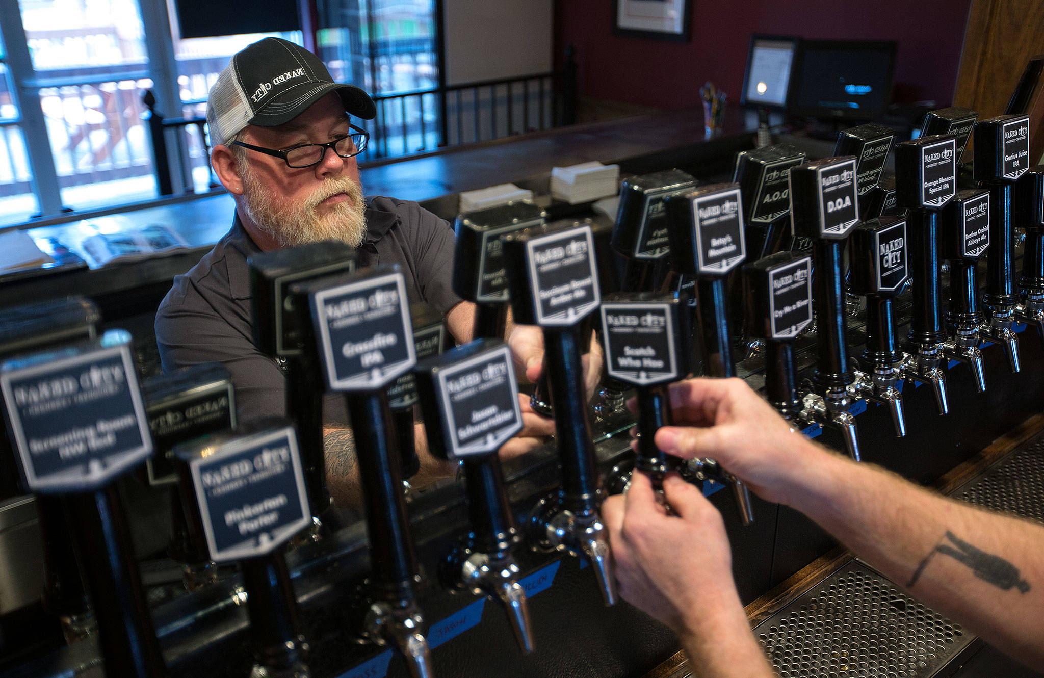 Owner Don Webb labels tap handles as he works to get Naked City Brewery ready for its soft opening on April 20 on Camano Island. (Andy Bronson / The Herald)