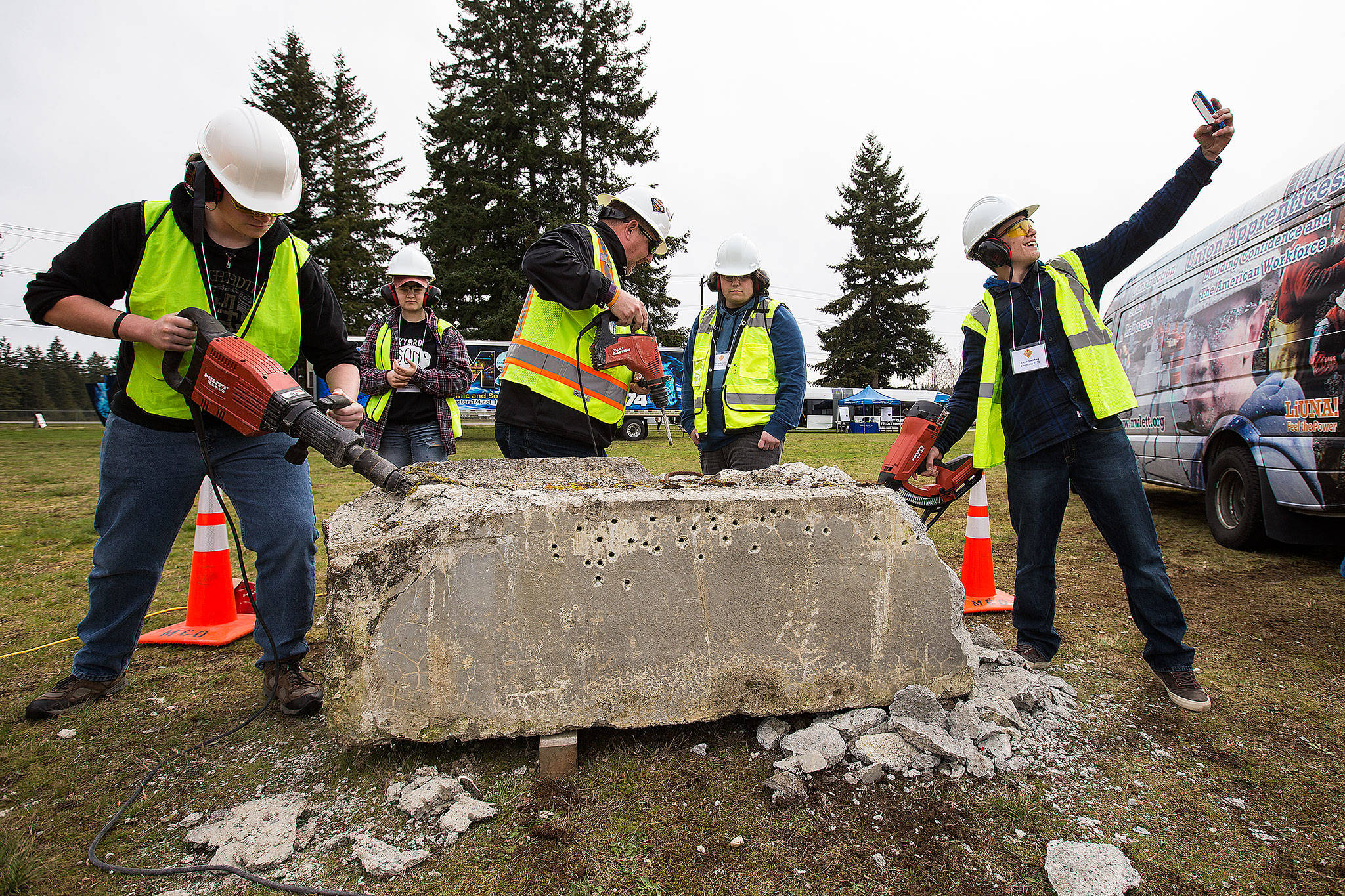 Jacob Smithies takes a selfie as fellow teens try out various tools on a concrete block during the Trade UP event at the Arlington Airport on Tuesday. (Andy Bronson / The Herald)