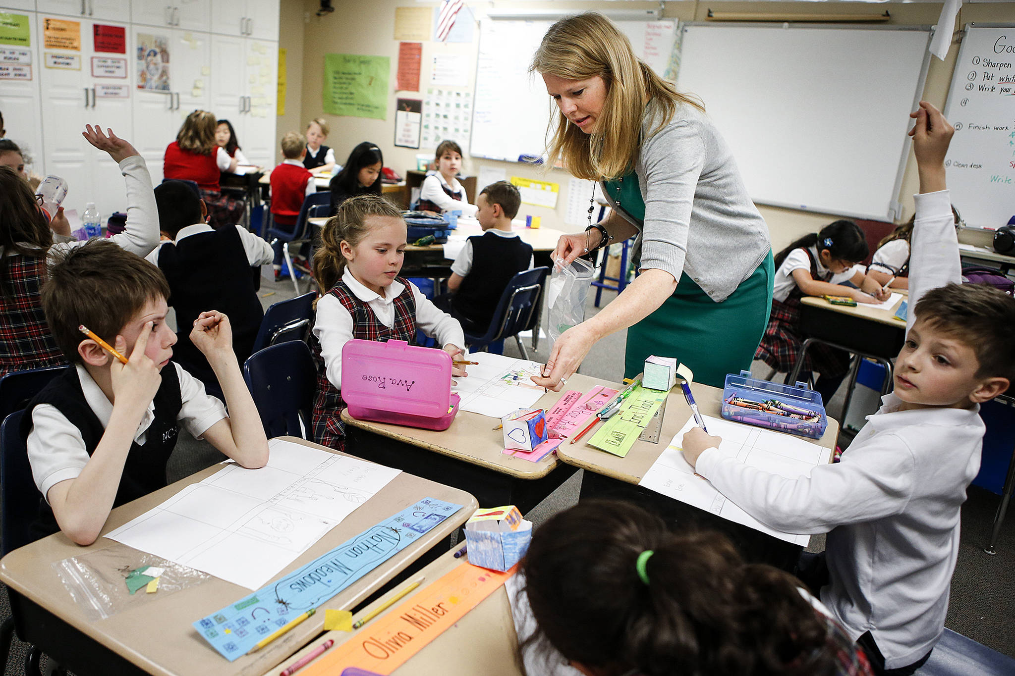 Second grade teacher Stephanie Hill helps students with an Easter assignment. (Ian Terry / The Herald)