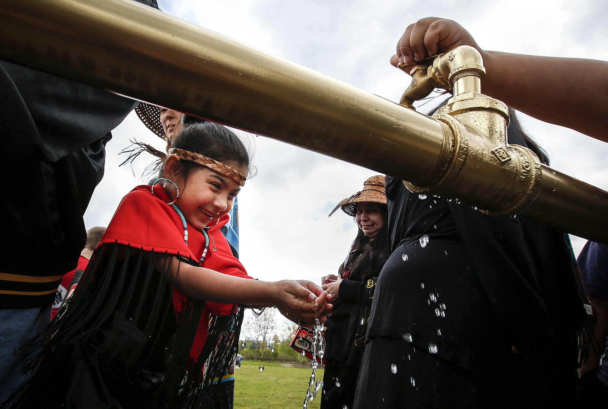 Belle Mahoney, 6, laughs as fresh water runs through her hands from a faucet opened Friday at the Tulalip Reservation during a ceremony to celebrate a newly opened water line that will provide clean drinking water to Tulalip. (Ian Terry / The Herald)