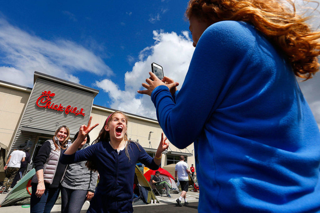A girl jumps in front of the camera as another girl takes a picture at the opening of the Lynnwood Chick-Fil-A in 2015. The popular fast-food restaurant is opening in Bothell and continues to see explosive growth despite past controversies. (File photo)
