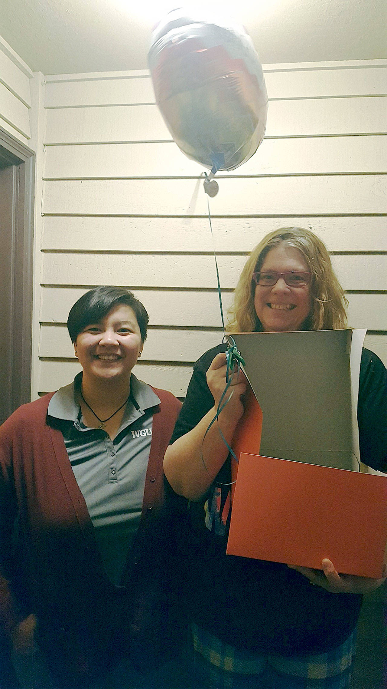 WGU Washington mentor Jen Liptrap (left) surprises Paula Kohring at her Everett apartment with the news that Kohring was chosen to receive a $10,000 scholarship. (Contributed photo)