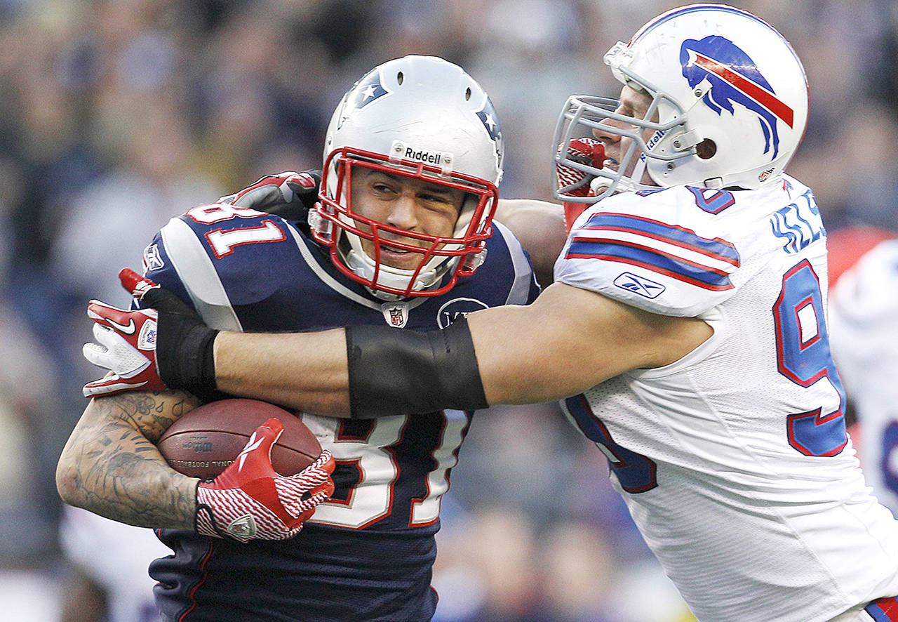 In this Jan. 1, 2012 photo, New England Patriots tight end Aaron Hernandez (81) tries to break free of Buffalo Bills linebacker Chris Kelsay (90) during the fourth quarter of an NFL football game in Foxborough, Massachusetts. (AP Photo/Elise Amendola, File)
