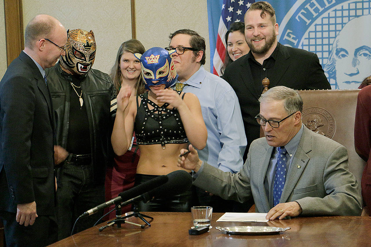 Gov. Jay Inslee talks with supporters of theatrical wrestling Monday in Olympia before signing a bill that creates a license for theatrical wrestling schools. Under the measure, any licensed theatrical wrestling school would be allowed to schedule a certain number of public performances. (AP Photo/Rachel La Corte)