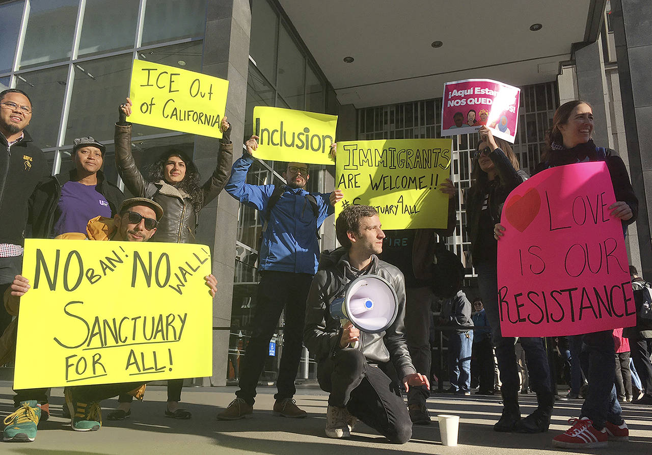Protesters hold up signs outside a courthouse where a federal judge will hear arguments in the first lawsuit challenging President Donald Trump’s executive order to withhold funding from communities that limit cooperation with immigration authorities Friday, April 14, in San Francisco. (AP Photo/Haven Daley)