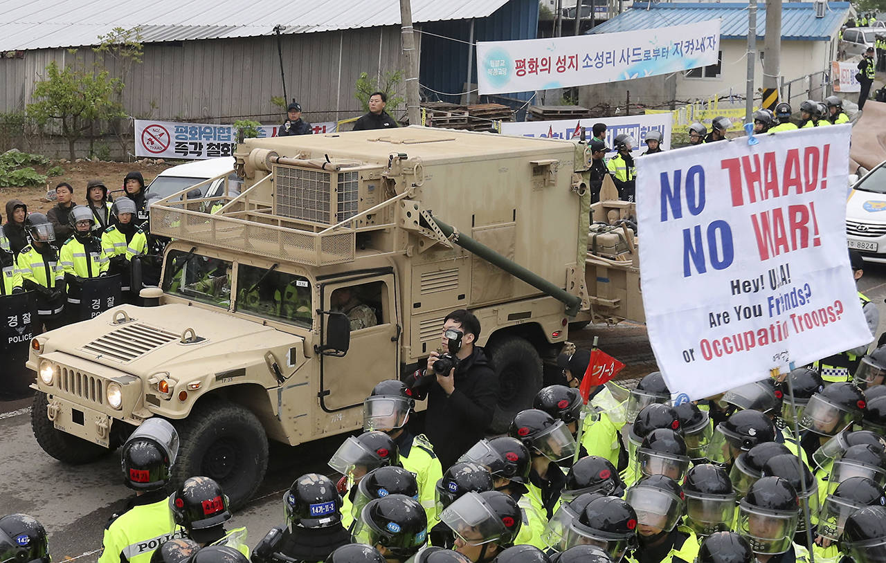 U.S. military vehicle moves past banners opposing a plan to deploy an advanced U.S. missile defense system called Terminal High-Altitude Area Defense, or THAAD, as South Korean police officers stand guard in Seongju, South Korea on Wednesday, April 26. South Korea says key parts of a contentious U.S. missile defense system have been installed a day after rival North Korea showed off its military power. (Kim Jun-hum/Yonhap via AP)