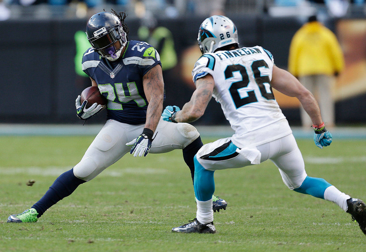 Seahawks running back Marshawn Lynch (24) carries the ball while Panthers defensive back Cortland Finnegan (26) closes in during a game Jan. 17, 2016, in Charlotte, N.C. (AP Photo/Bob Leverone)