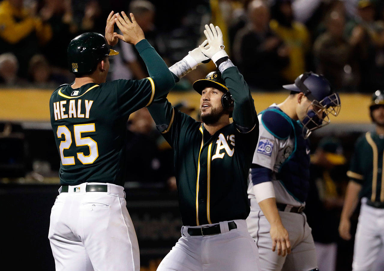 The Athletics’ Trevor Plouffe (center) celebrates his three-run home run with Ryon Healy (25) during the seventh inning of a game against the Mariners on April 20, 2017, in Oakland, Calif. (AP Photo/Marcio Jose Sanchez)