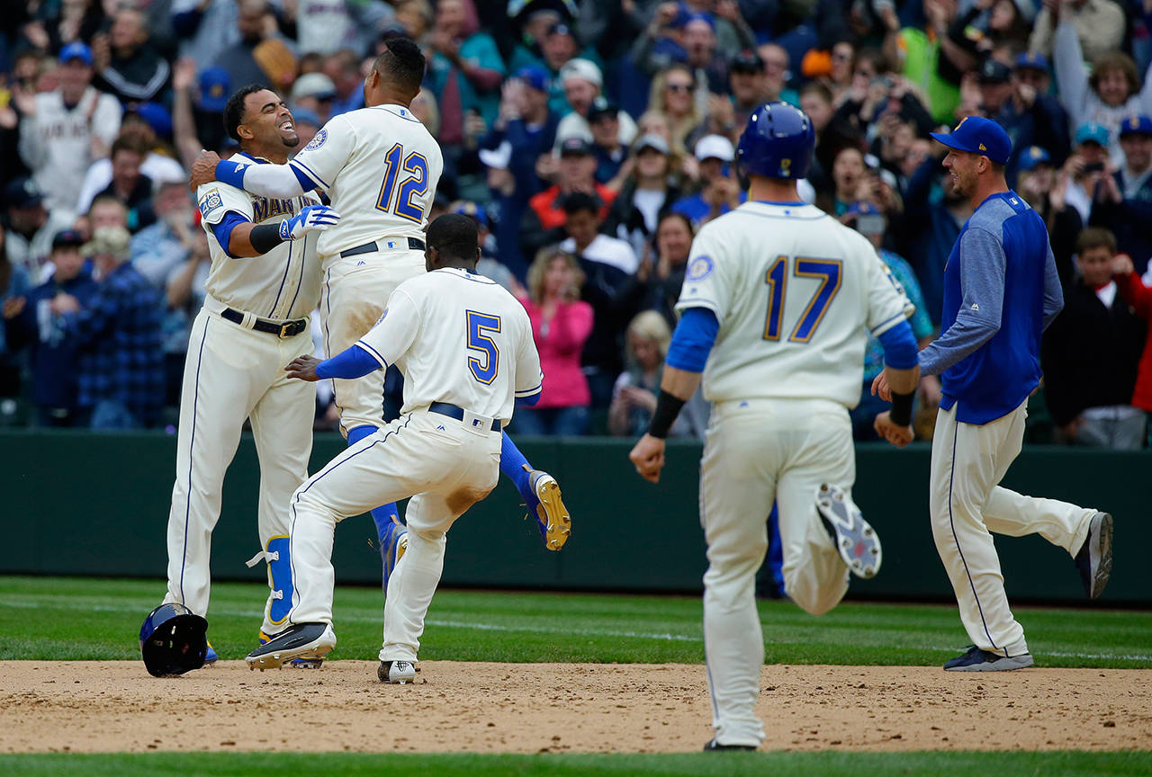 Seattle Mariners’ Nelson Cruz, left, is greeted by teammates including Leonys Martin (12) and Guillermo Heredia (5) after Cruz hit a walk-off single in the ninth inning to score Mariners’ Mike Freeman and give the Mariners a 8-7 win over the Texas Rangers, Sunday, April 16, 2017, in Seattle. (AP Photo/Ted S. Warren)