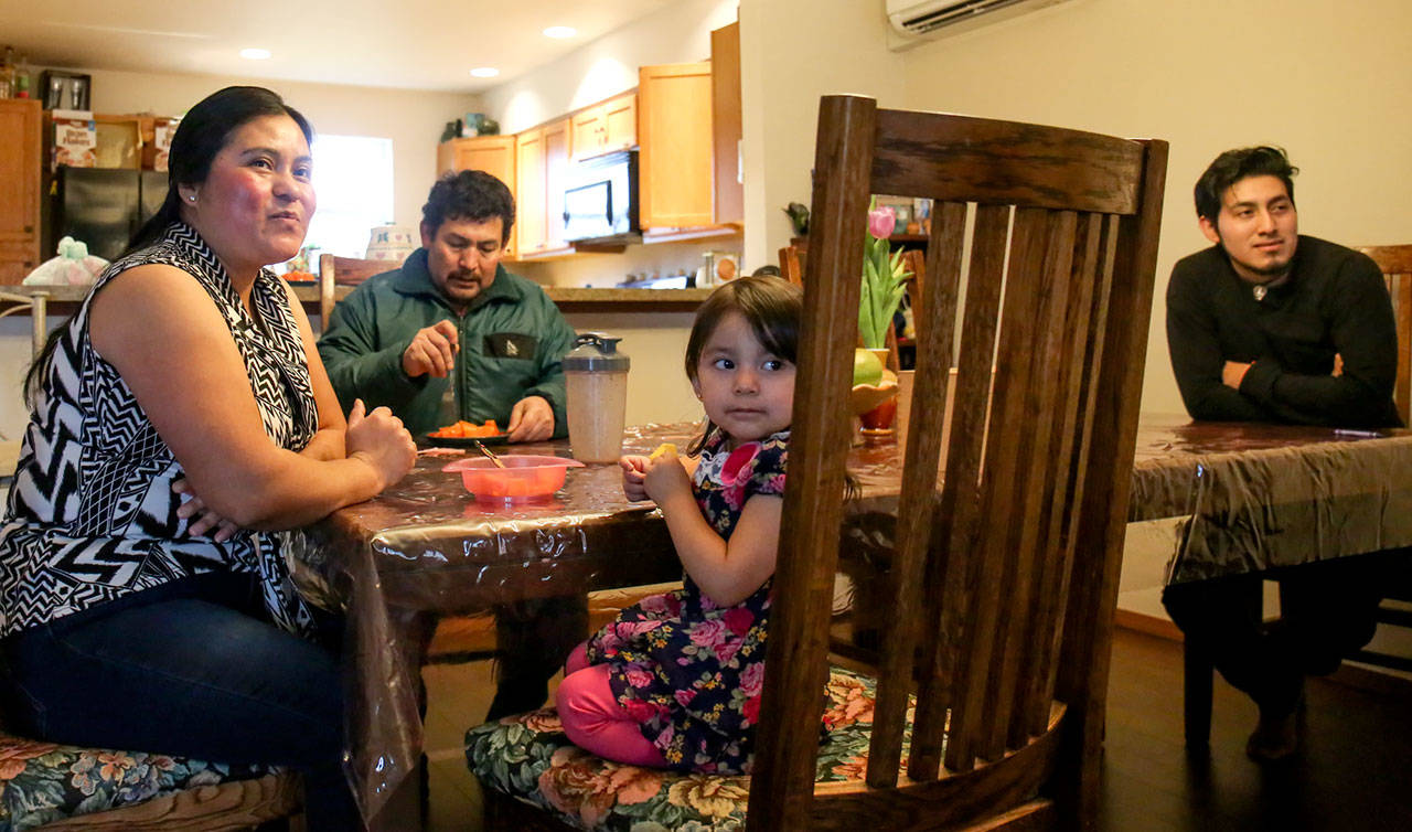 Justina Hernandez-Antonio, Eutiquio Martinez-Garcia, and their children Ernesto Martinez-Hernandez and Maritza, watch TV at their new home in Monroe. (Kevin Clark / The Herald)