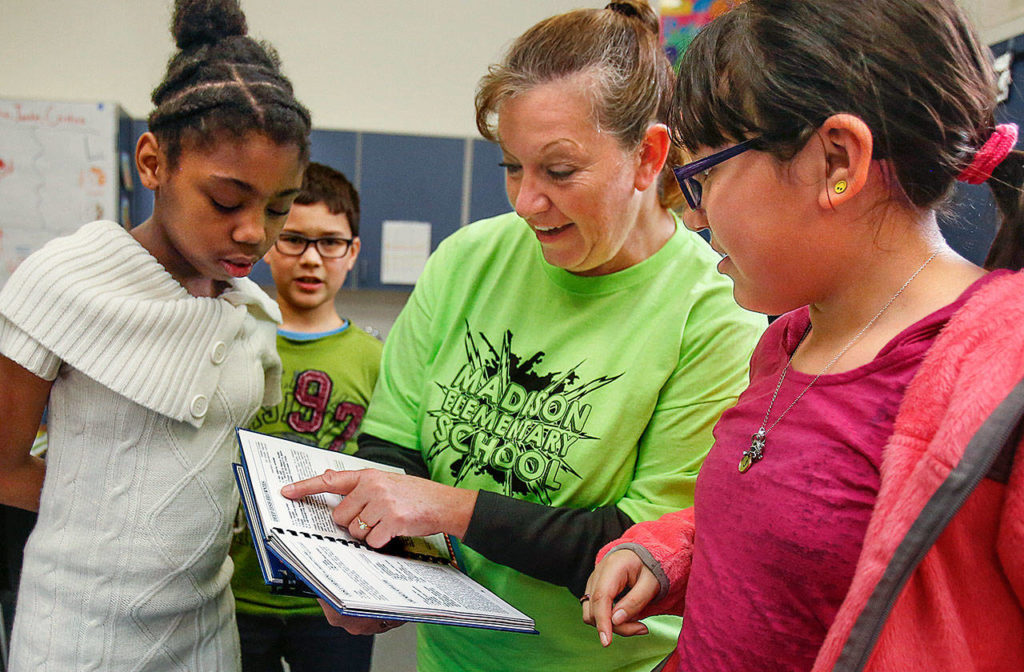Madison Elementary School fifth-graders Jaila Snowden (left) Jaedin Chum and Jaimy Moreno (right) listen to their teacher, Teresa O’Shea talk about her deep-dish brownie recipe. O’Shea contributed five recipes in the book. (Dan Bates / The Herald)
