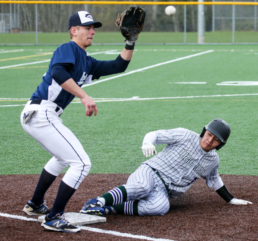 Edmonds-Woodway’s Jacob Kitchen (right) beats the throw to Meadowdale’s Hunter Shouse at third base during a game April 12, 2017, at Mountlake Terrace High School. (Kevin Clark / The Herald)
