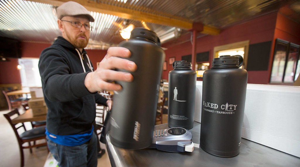 Owner Bryan Miller grabs growlers for a display as he, co-owner Don Webb and staff work to get Naked City Brewery ready for its soft opening on April 20 on Camano Island. (Andy Bronson / The Herald)
