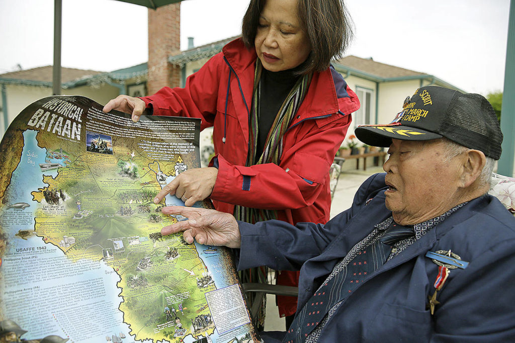 In this photo taken Thursday, April 6, Bataan Death March survivor Ramon Regalado looks over a map showing where he marched with Cecilia Gaerlan outside his home in El Cerrito, California. (AP Photo/Eric Risberg)
