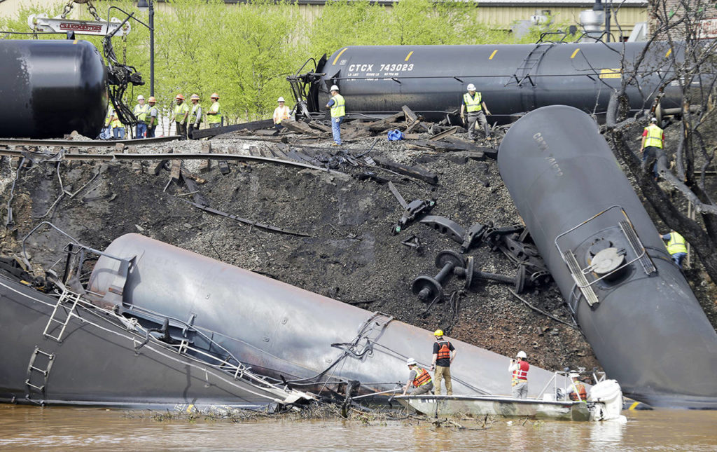 In this May 1, 2014, photo, survey crews in boats look over tanker cars as workers remove damaged tanker cars along the tracks where several CSX tanker cars carrying crude oil derailed and caught fire along the James River near downtown Lynchburg, Virgina. (AP Photo/Steve Helber, File)
