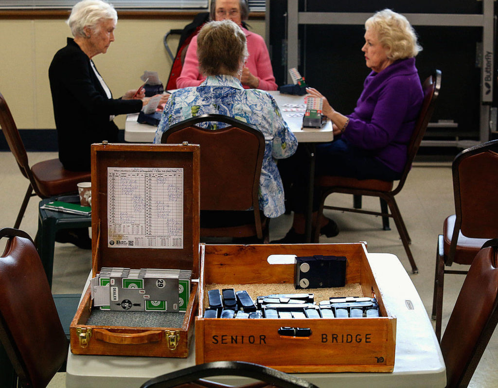 Sitting on a table in the center of the room, two hand-crafted cedar boxes hold card decks and other important materials used in playing bridge. They were made by long-time club member John Marchetti, 99, of Everett. (Dan Bates / The Herald)
