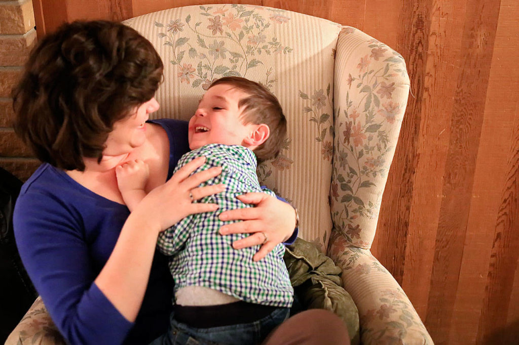 Deanna Fisher tickles her youngest autistic son, Colin, 4, at their home in Bothell. (Kevin Clark / The Herald)
