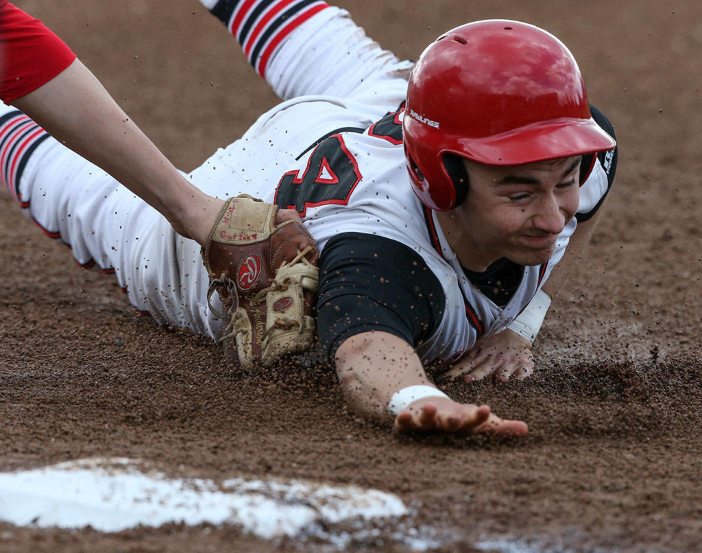 Snohomish’s Josh Johnston slides safely to third base, tagged by an empty glove, during a game against Marysville Pilchuck on April 18, 2017, in Snohomish. (Andy Bronson / The Herald)
