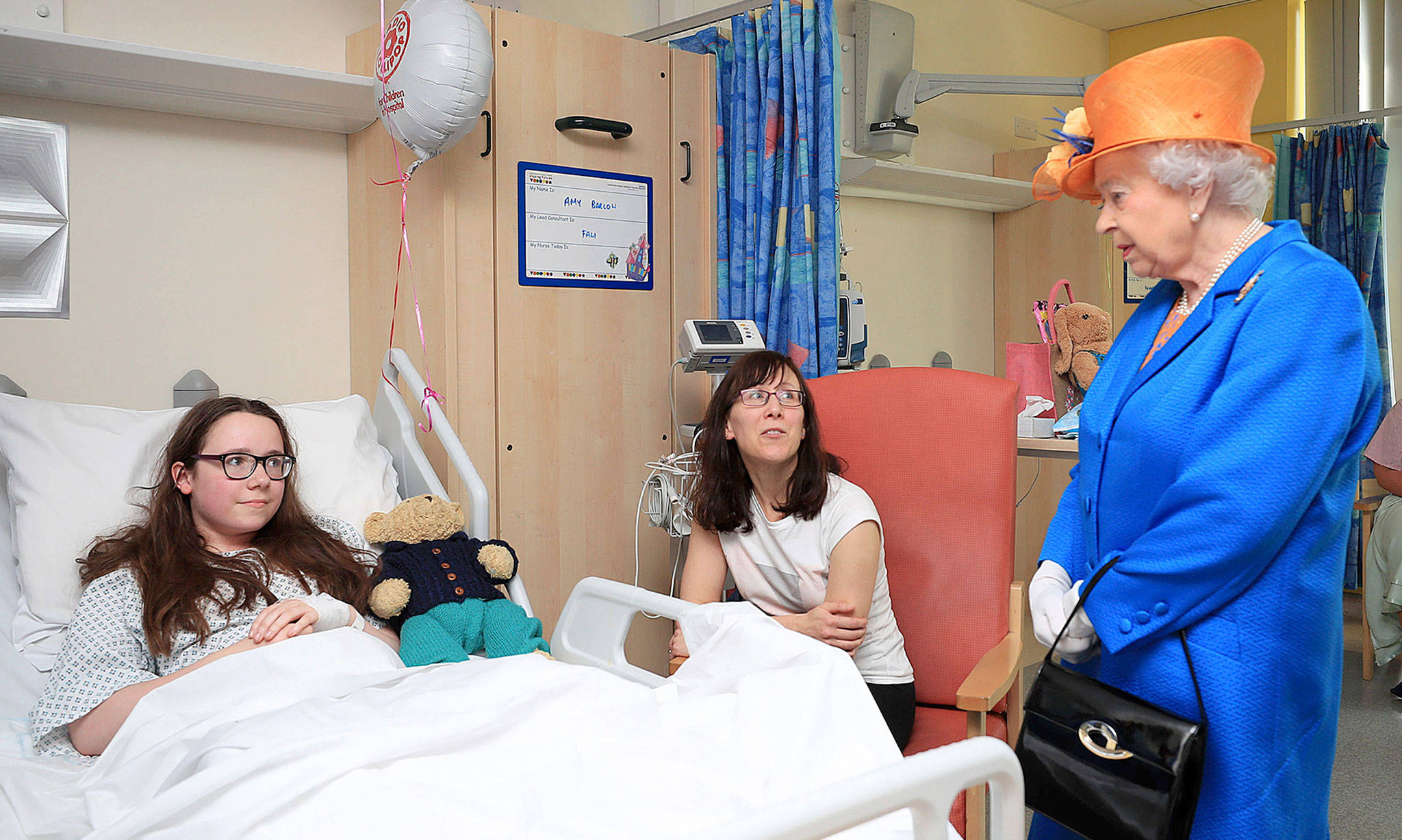 Britain’s Queen Elizabeth II (right) speaks to Amy Barlow (left), 12, from Rawtenstall, Lancashire, and her mother, Kathy, on Thursday at the Royal Manchester Children’s Hospital in Manchester England. The queen met with victims of the terror attack in the city earlier this week. (Peter Byrne/Pool via AP)