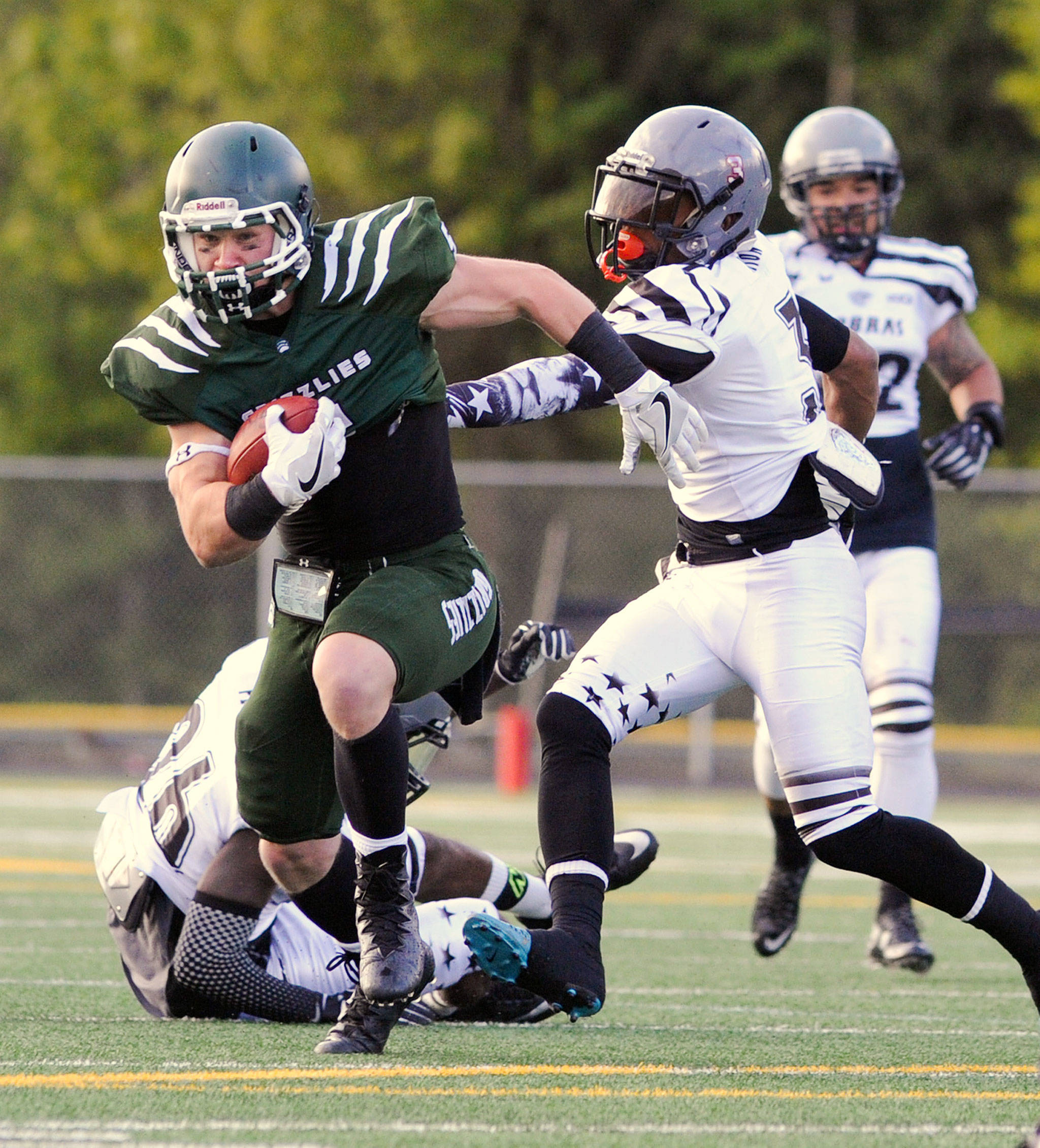 Arlington running back Jeff Hanson avoids the reach of Cowlitz Cobra defender Daniil Karpyuk on his way to a touchdown Saturday during the Grizzlies’ season opener at John C. Larson Stadium in Arlington. (Doug Ramsay / For The Herald)