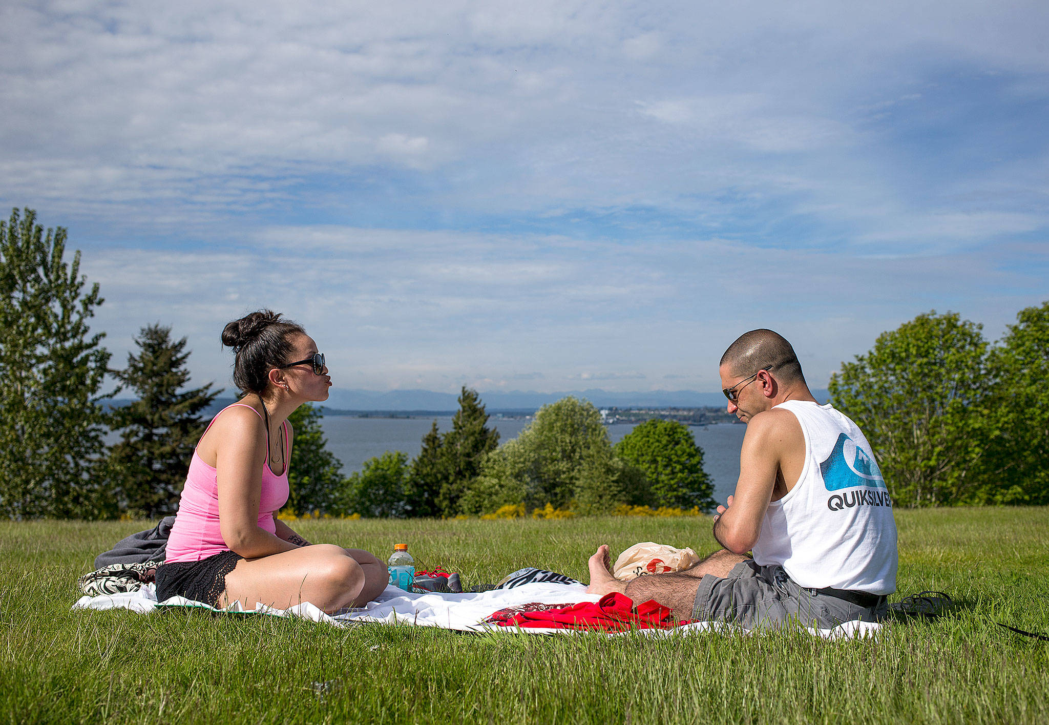 Tawny Mandracken blows a teasing kiss at her husband, Garrick, after he lost a round of cards as the duo enjoys the sunny weather at Harborview Park on Tuesday in Everett. (Andy Bronson / The Herald)