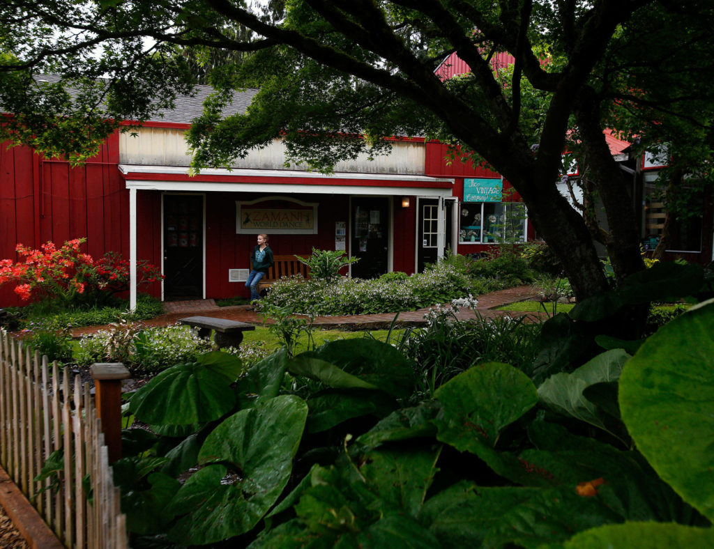 On a drizzly afternoon, Thursday, a girl finds cover on the arm of a bench at the edge of another cozy setting at Bothell’s Country Village. The unique village atmosphere provides something special. The family that owns the Country Village, however, has signed a letter of intent with a national developer to sell the property contingent on a feasibility study. (Dan Bates / The Herald)
