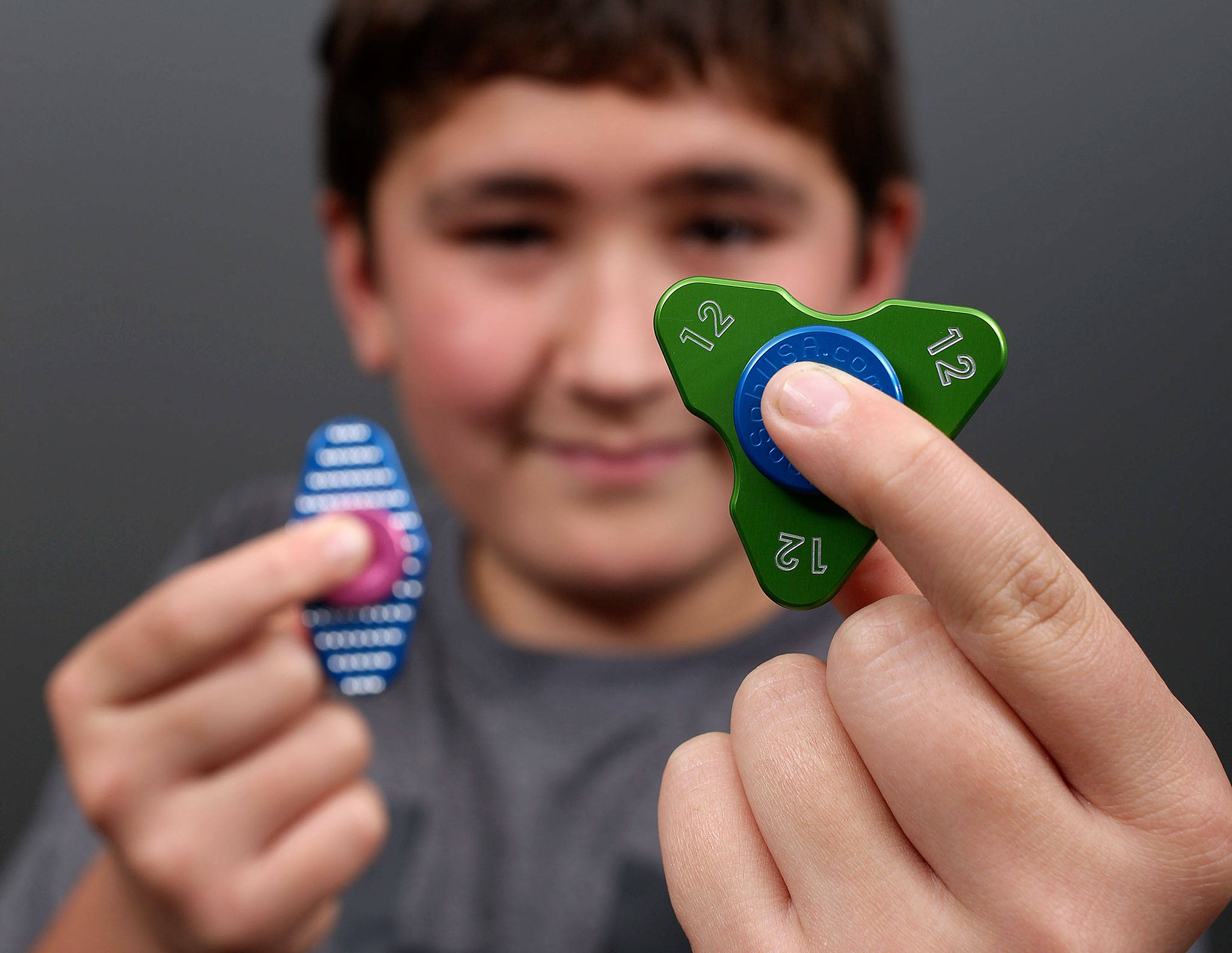 Blake Branch, 12, holds two of the many fidget spinners made by his family-owned business, Tech Machining USA in Mount Vernon. (Andy Bronson / The Herald)
