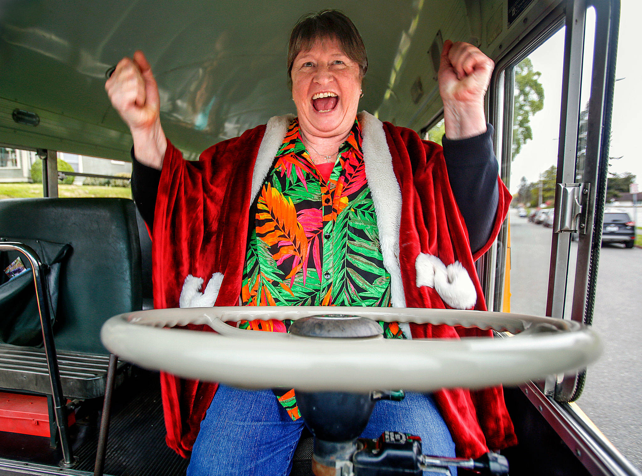 A delighted Sue Cheffer climbs into the driver’s seat of a vintage Crown Motor Coach school bus when fellow drivers at Everett School District’s bus barn at 37th and Oakes surprised her with a party and a ride Wednesday, just two days before her retirement. (Dan Bates / The Herald)