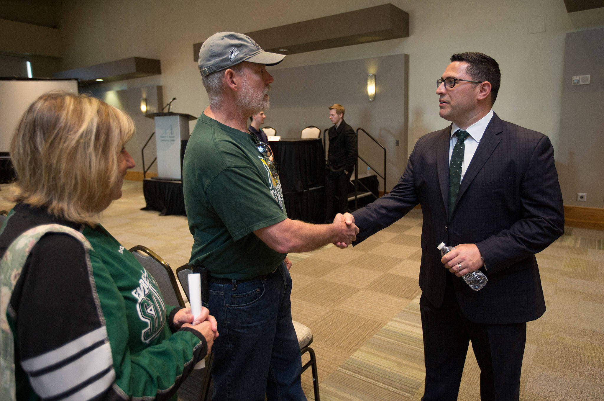 New Silvertips head coach Dennis Williams shakes hands with longtime season ticketholders Doris Rupert and Tom Rupert on Monday at the Edward D. Hansen Conference Center in Everett. (Andy Bronson / The Herald)