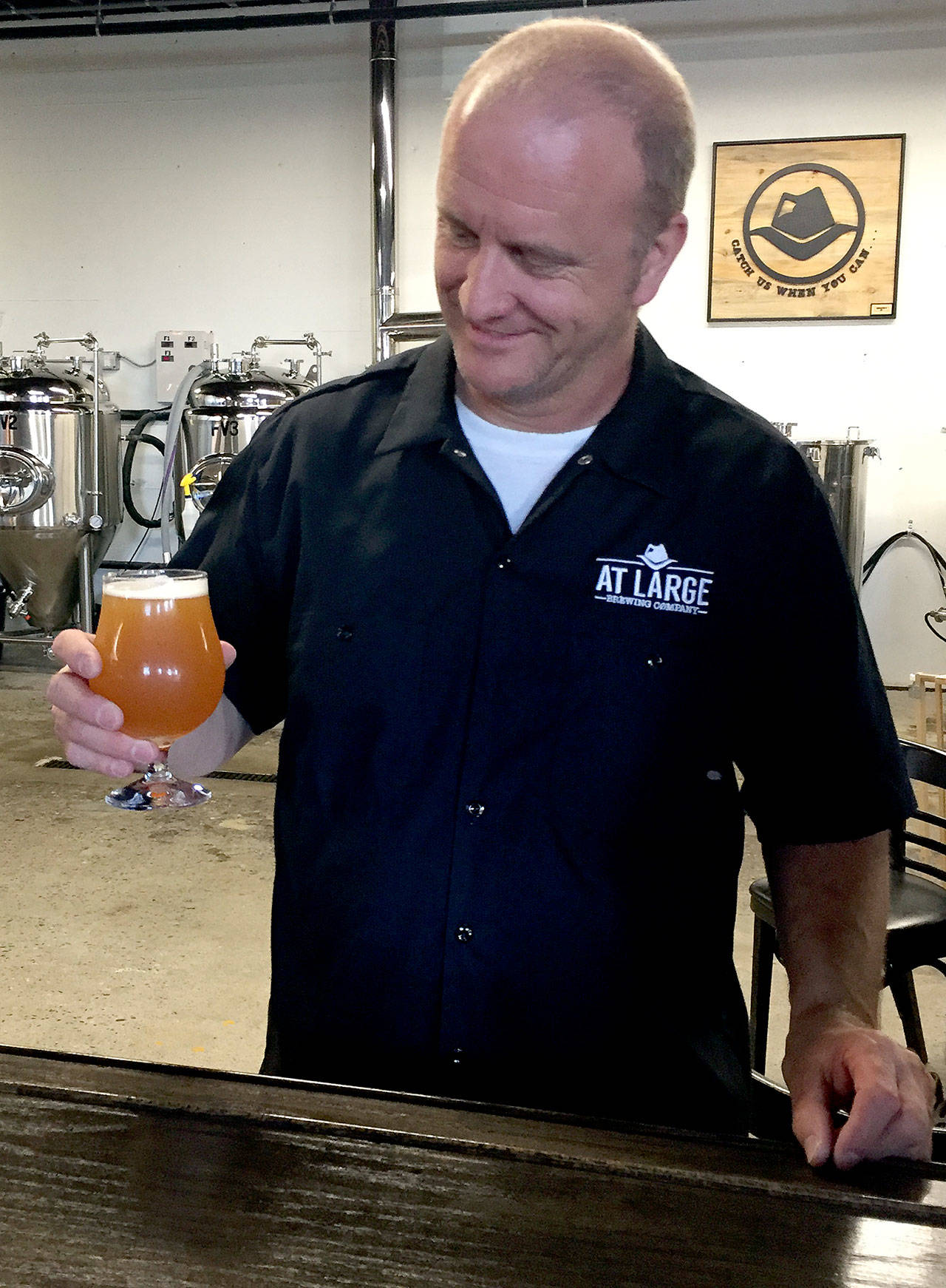 Jim Weisweaver, co-owner of At Large Brewery, celebrates the one-year anniversary of opening the brewery on the Everett waterfront with a pint of The Chicago Typewriter. The New England-style IPA shares the nickname of Al Capone’s Tommy gun. (Photo by Aaron Swaney)