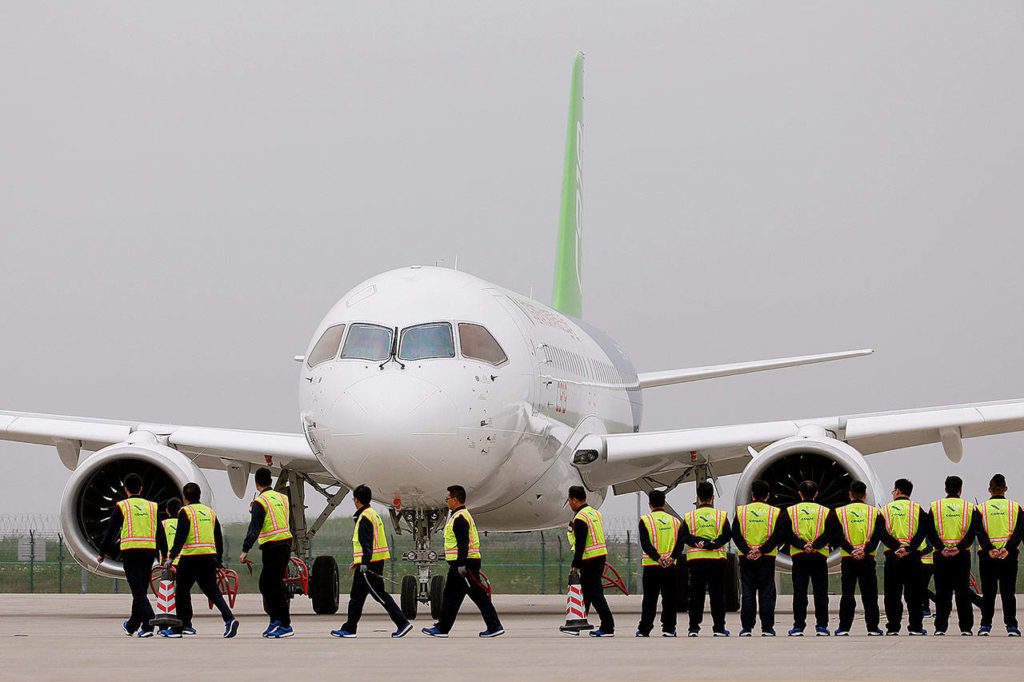 Members of staff stand in front of China’s home-grown C919 passenger jet after it landed on its maiden flight at the Pudong International Airport in Shanghai, China, on Friday. (Aly Song/Pool Photo via AP)
