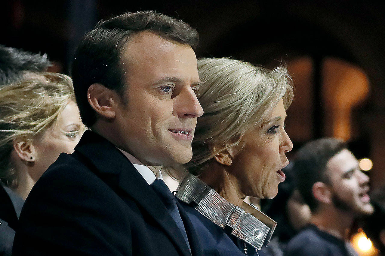 Incoming French President Emmanuel Macron (left) and his wife, Brigitte Macron, sing the national anthem after he delivered a speech in front of the Pyramid at the Louvre Museum in Paris on Sunday. (Thomas Samson/Pool Photo via AP)