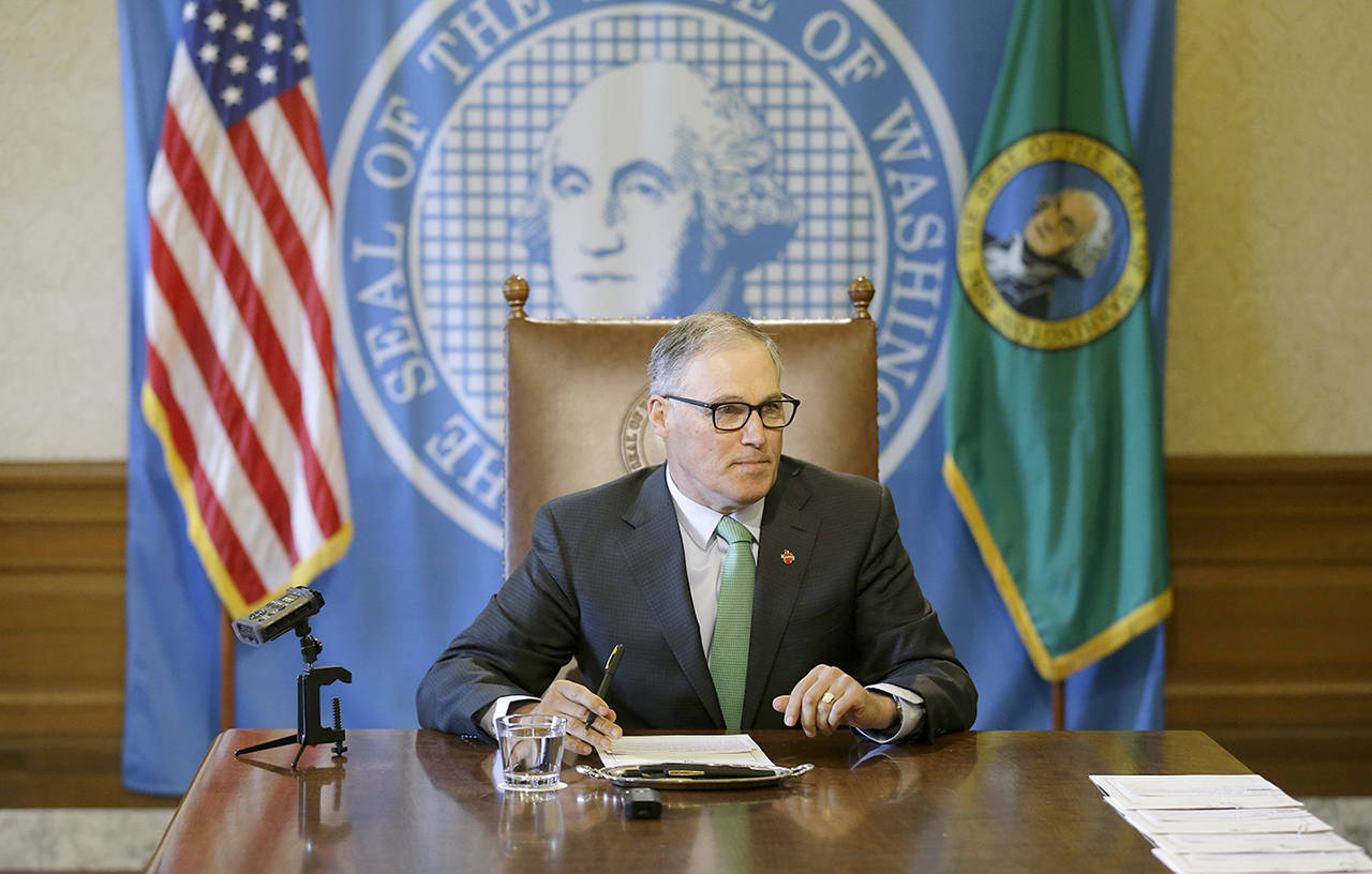 Gov. Jay Inslee sits at a table prior to a bill-signing ceremony on April 19 at the Capitol in Olympia. (AP Photo/Ted S. Warren, file)