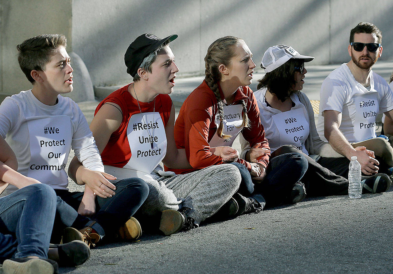 Protesters lock arms as they block a driveway at the U.S. Citizen and Immigration Services building in San Francisco on Monday. (AP Photo/Jeff Chiu)