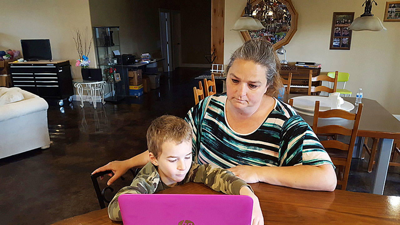 Talitha Merritt helps her son, Preston, 7, work on an interactive school assignment at his home in Walla Walla. Preston is enrolled in the first grade through Washington Connection Academy, an online school that was approved in the state in 2016. (Sheila Hagar / Walla Walla Union-Bulletin)