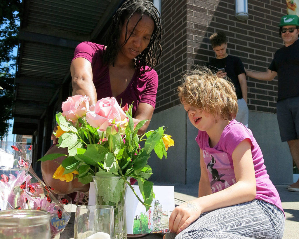 Angel Sauls helps her stepdaughter, Coco Douglas, arrange a sign and some painted rocks she made for a memorial in Portland, Oregon, on Saturday for two bystanders who were stabbed to death Friday while trying to stop a man who was yelling anti-Muslim slurs and acting aggressively toward two young women. (Gillian Flaccus / Associated Press)
