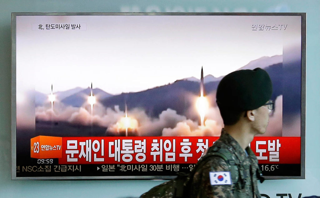 A South Korean army soldier walks by a TV news program showing a file image Sunday of missiles being test-launched by North Korea, at the Seoul Railway Station in Seoul, South Korea. North Korea on Sunday test-launched a ballistic missile that landed in the Sea of Japan, the South Korean, Japanese and U.S. militaries said. The launch is a direct challenge to the new South Korean president elected four days ago and comes as U.S., Japanese and European navies gather for joint war games in the Pacific. The signs read: “The first provocation since the inauguration of President Moon Jae-in.” (AP Photo/Ahn Young-joon)
