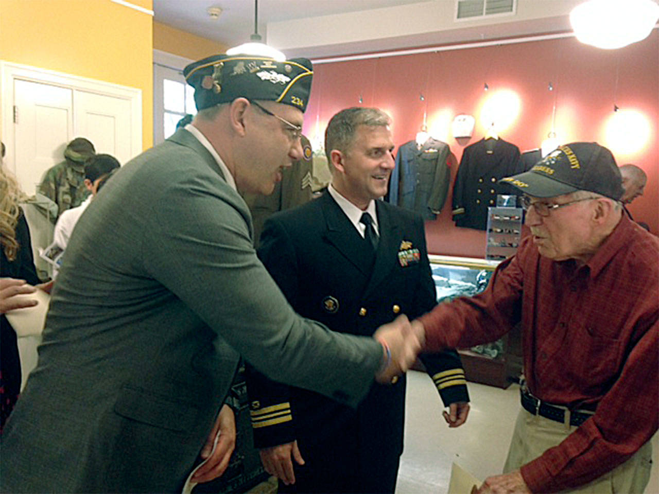 Chris Szarek, director of Edmonds Community College’s Veterans Resource Center, and Lt. Cmdr. Brad Coleman of Naval Station Everett greet an unidentified World War II veteran at the May 6 grand opening of the Northwest Veterans Museum in Lynnwood. (Contributed photo)