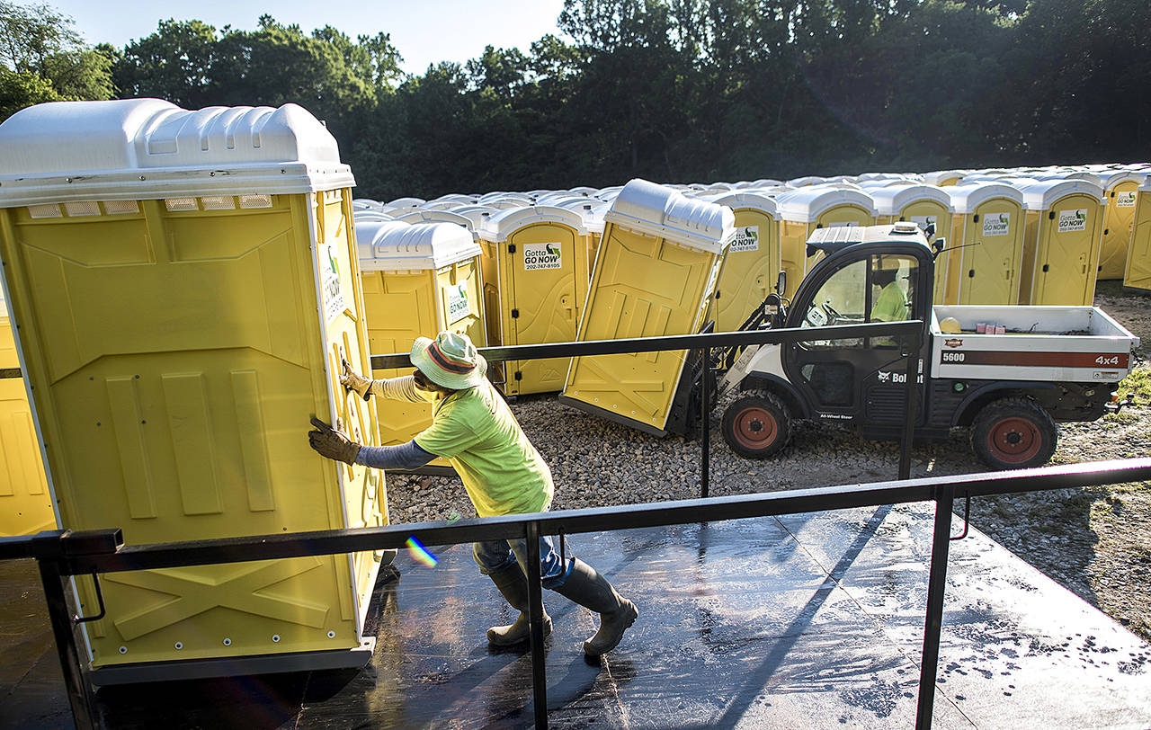 Gotta Go Now portable toilets owner Frederick Hill III loads porta-potties onto trucks for delivery with the help of Chris Lopez (left) in Upper Marlboro, Maryland. (Melina Mara / Washington Post)