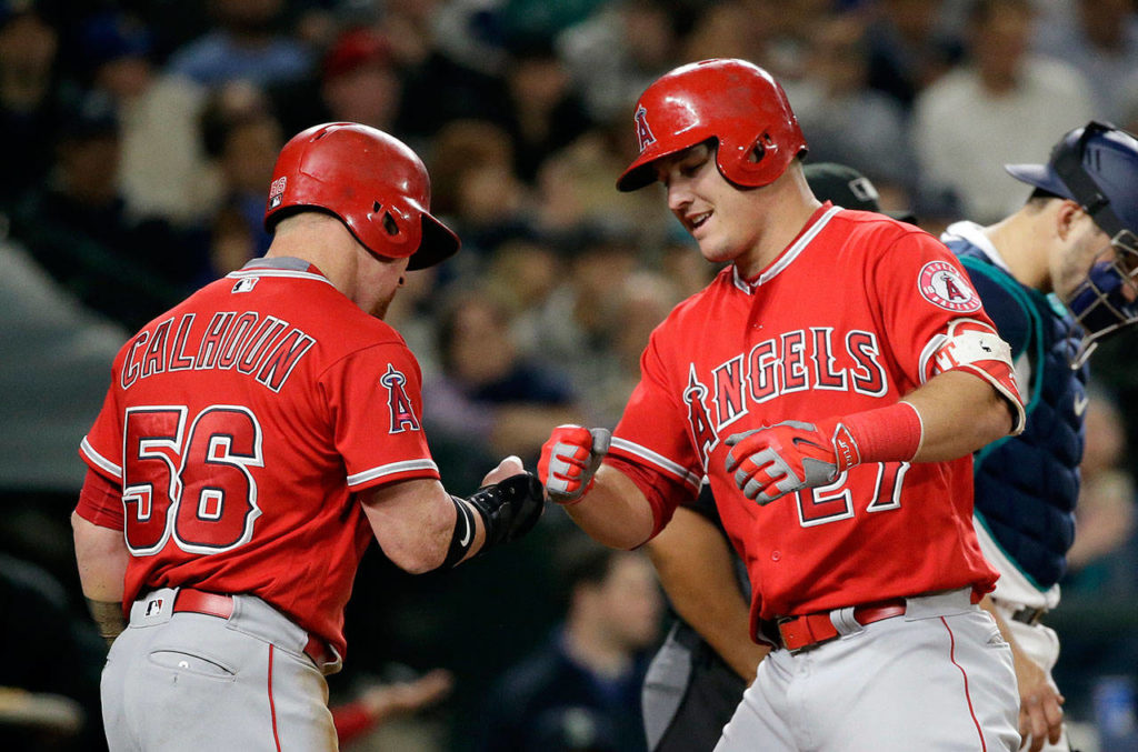 The Angels’ Kole Calhoun (56) greets Mike Trout at home after Trout’s two-run home run against the Mariners in the sixth inning of a game May 3, 2017, in Seattle. (AP Photo/Elaine Thompson)
