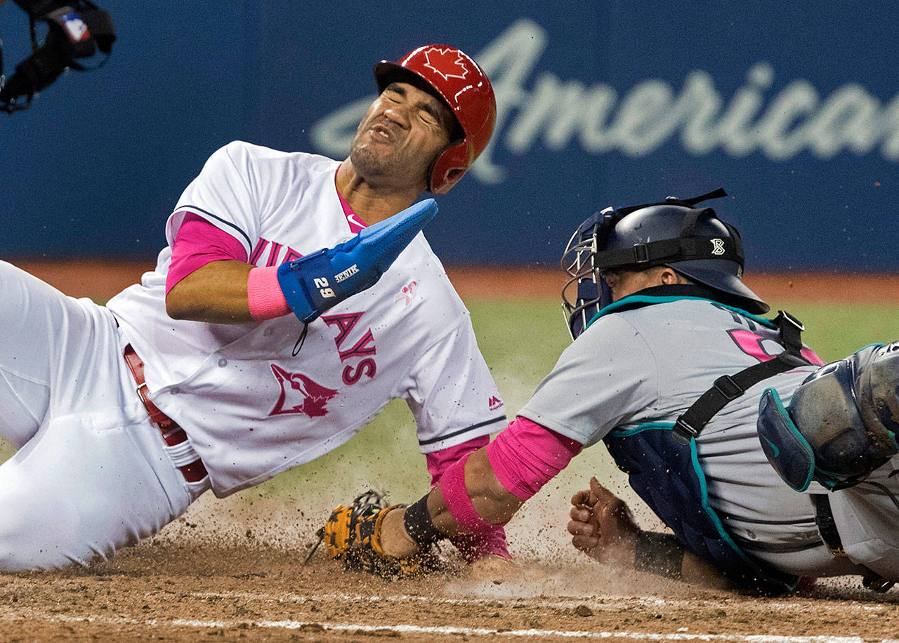 The Blue Jays’ Devon Travis steals home beating the tag attempt by Mariners catcher Carlos Ruiz in the eighth inning of a game May 13, 2017, in Toronto. (Fred Thornhill/The Canadian Press via AP)