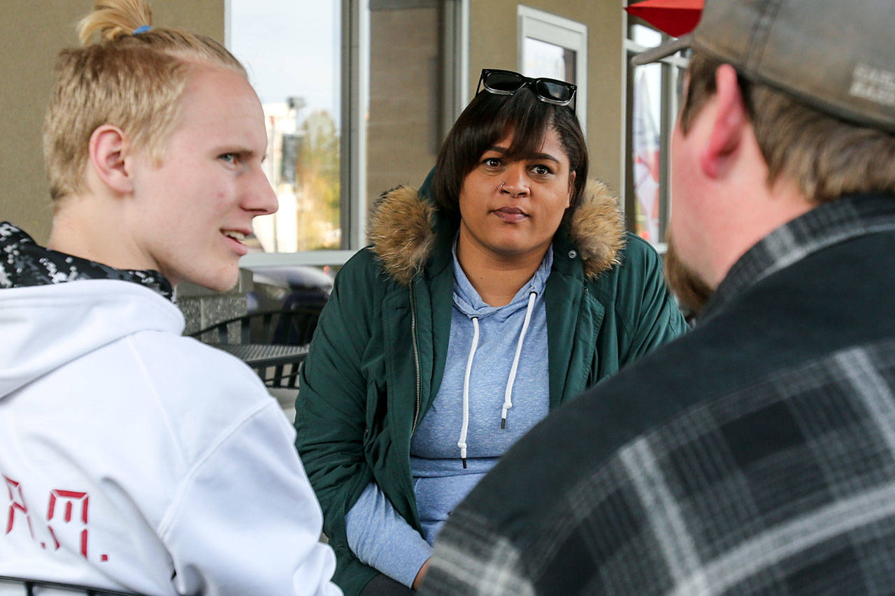 Whitney Hooks, center, listens to the Robert Griffith, right, father of potential client, Rylee Griffith, in Everett on March 31. The four-time state champion shot put thrower from Cascade High School has returned to the area to train and mentor young people. (Kevin Clark / The Herald)