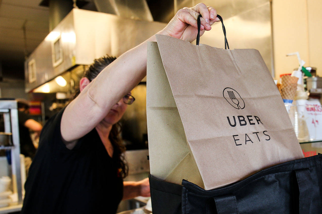 LaRae Richards loads an order for deliver via Uber Eats at Red Onion Burgers in Mountlake Terrace. (Kevin Clark / The Herald)