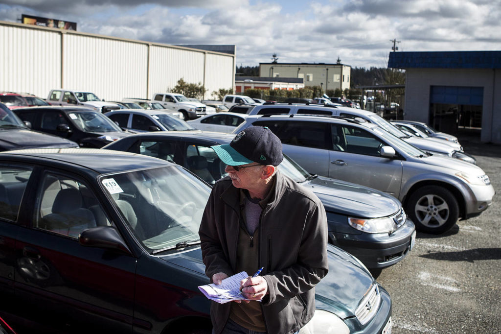 Car dealer K.C. Crandall, of Burlington, jots down notes about a car after test driving it at a dealer auction at Kaman Auctions in Edmonds. (Ian Terry / The Herald)
