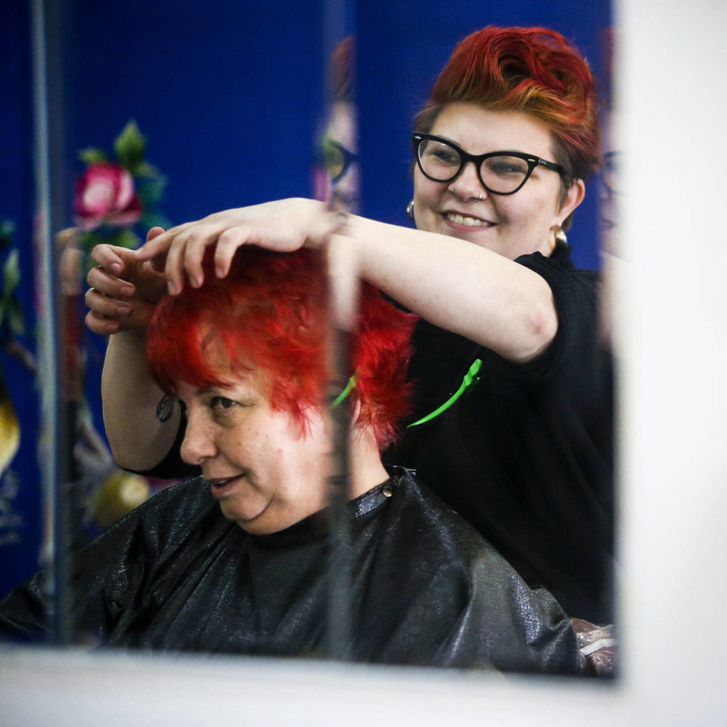 Melissa Castleman (right) smiles as client Corky Montgomery checks out her new red hair color at Eclectik Salon in Everett on Friday, Feb. 17. Castleman specializes in hair coloring at her salon on North Broadway. (Ian Terry / The Herald)
