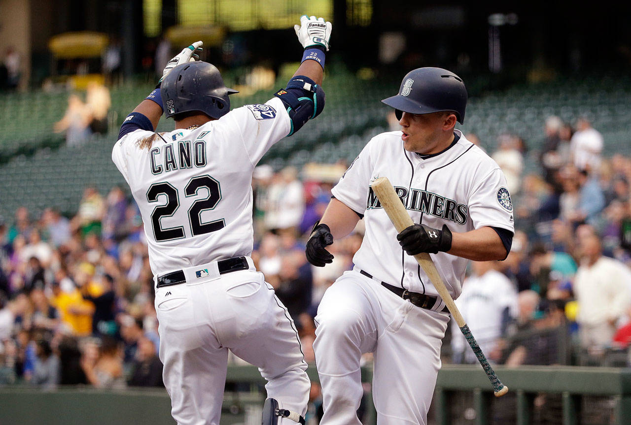The Mariners’ Robinson Cano (22) is congratulated by Kyle Seager after Cano’s solo home run against the Angels in the first inning of a game May 3, 2017, in Seattle. (AP Photo/Elaine Thompson)