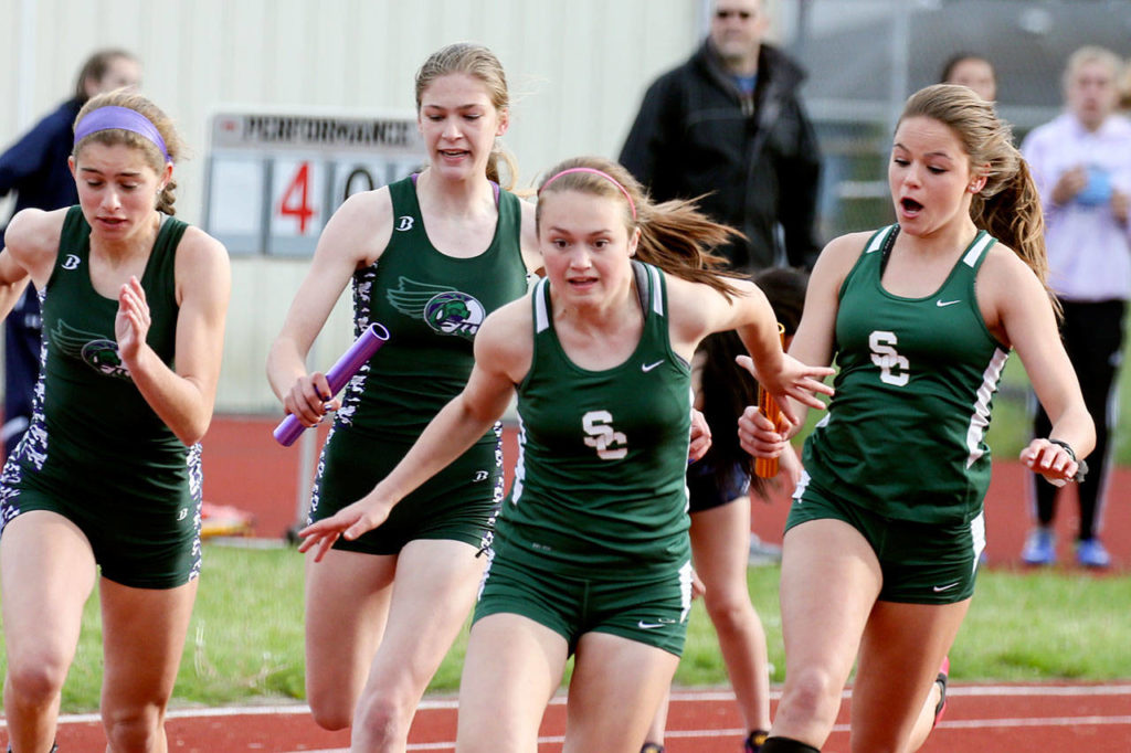 Shorecrest’s Sydney Brandt (far right) hands off to teammate Ronna Iverson and Edmonds-Woodway’s Hannah Hicks hands off to Gaby Chappell during the 4×100-relay at the Wesco 3A South track and field championships on May 12, 2017, at Edmonds Stadium. (Kevin Clark / The Herald)
