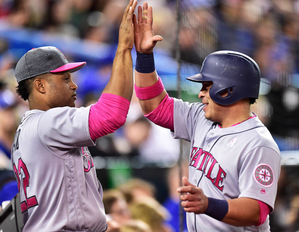 Seattle Mariners’ Robinson Cano (22) congratulates teammate Carlos Ruiz after Ruiz scored on a throwing error by Toronto Blue Jays outfielder Jose Bautista during fifth-inning baseball game action in Toronto, Sunday, May 14, 2017. (Frank Gunn/The Canadian Press via AP)
