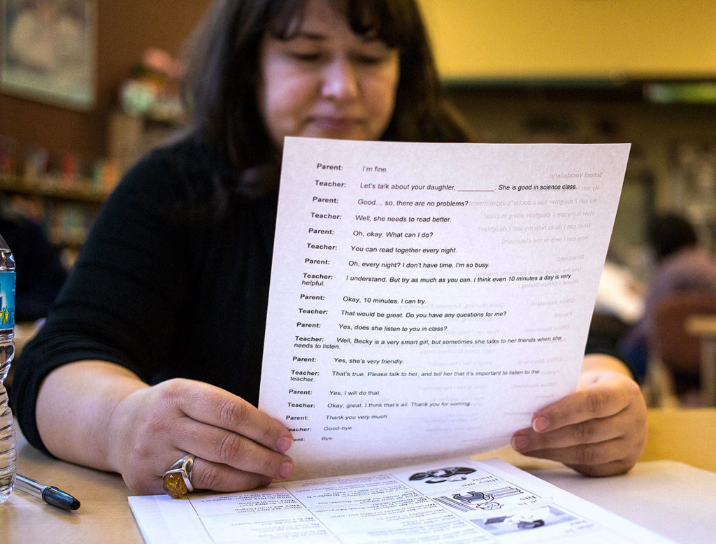 Valentina Andpilogova reads a phone conversation between a parent and a teacher during an ESL class in the library at Emerson Elementary on May 1 in Everett. (Andy Bronson / The Herald)
