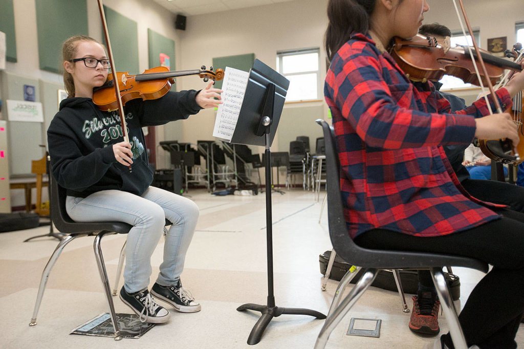 Everett High School’s Reilli Hopfauf holds her violin under her chin as she turns pages while playing in the Everett Youth Symphony Orchestra. (Andy Bronson / The Herald)
